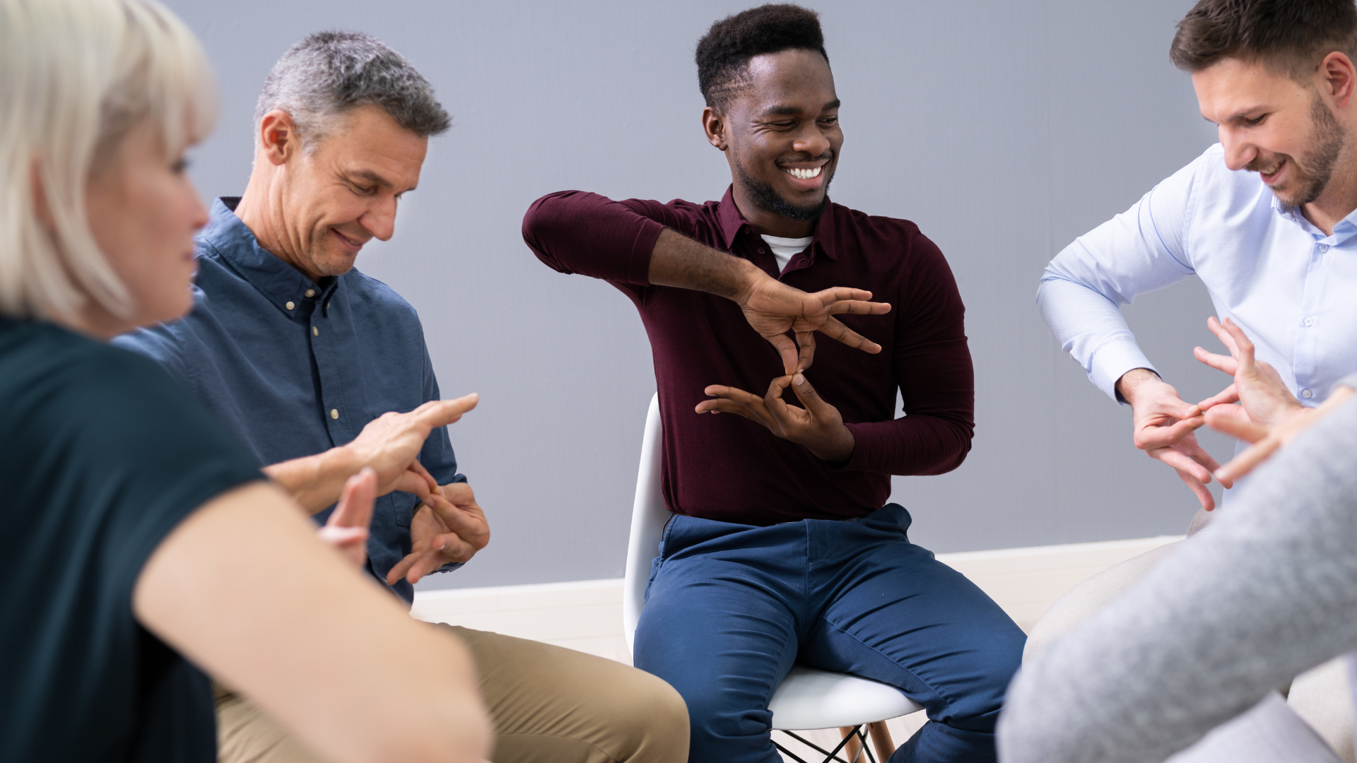 A young black man teaches sign language to a group of people